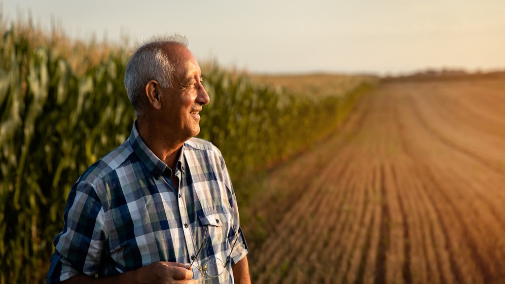 older farmer standing in front of his crops